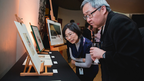 A man and a woman look intently at Japanese art 
