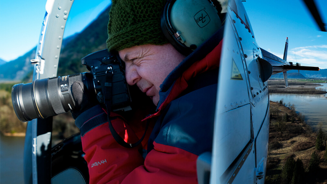 Andrew Wright taking a photograph in a helicopter.