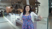 photo of Sarah in a purple dress standing in front of dinosaurs