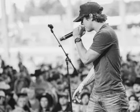 A man playing his guitar and singing in front of a crowd.