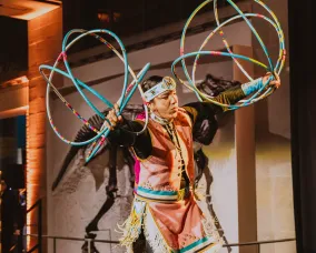 A person in aboriginal clothing doing a performance with hoops.