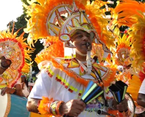 Bahamas Junkanoo Legends. A man with a bright orange helmet blowing a whistle.playing an 