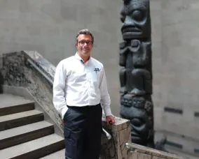 A man posing at the bottom of a stair case.