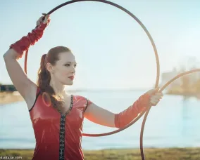 Bex wearing red latex holding red hula hoops in front of a lake.
