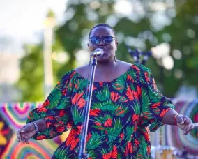 A woman stands on a stage singing to the audience.