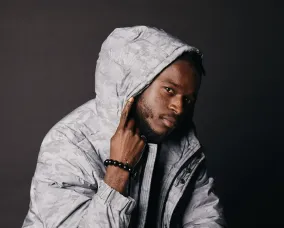 Borelson posing with his hood on and finger pointing up.