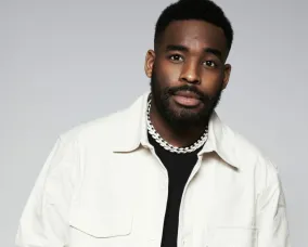 DJ Devo posing in front of a plain background.