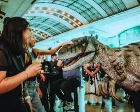 Museum visitors petting Sierra the Utahraptor.