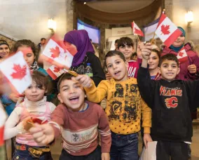 group of happy children waving Canadian flags