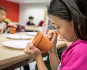 Student in the ROM Makerspace drawing with pencil on a clay pot