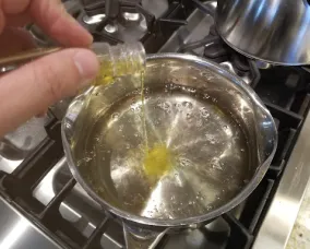 Yellow food colouring being mixed into boiling sugar solution.