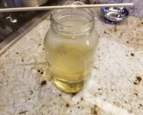 Kebab skewer across the top of the mason jar, knotted string dangling inside the jar in the sugar mixture