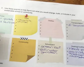 Un élève écrit dans une feuille de travail, réfléchissant à des solutions durables dans différentes catégories.