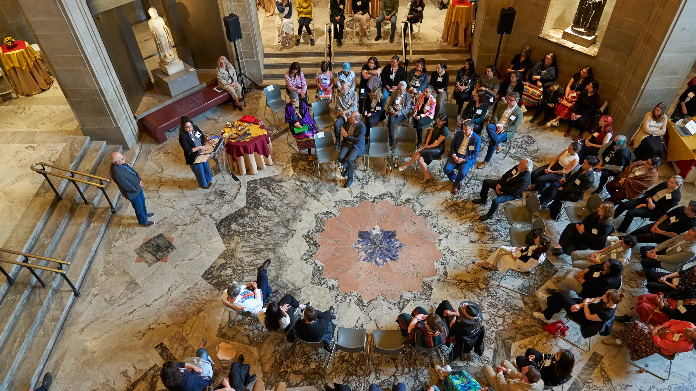 Presentation attendees in a large circle listening to a presentation.