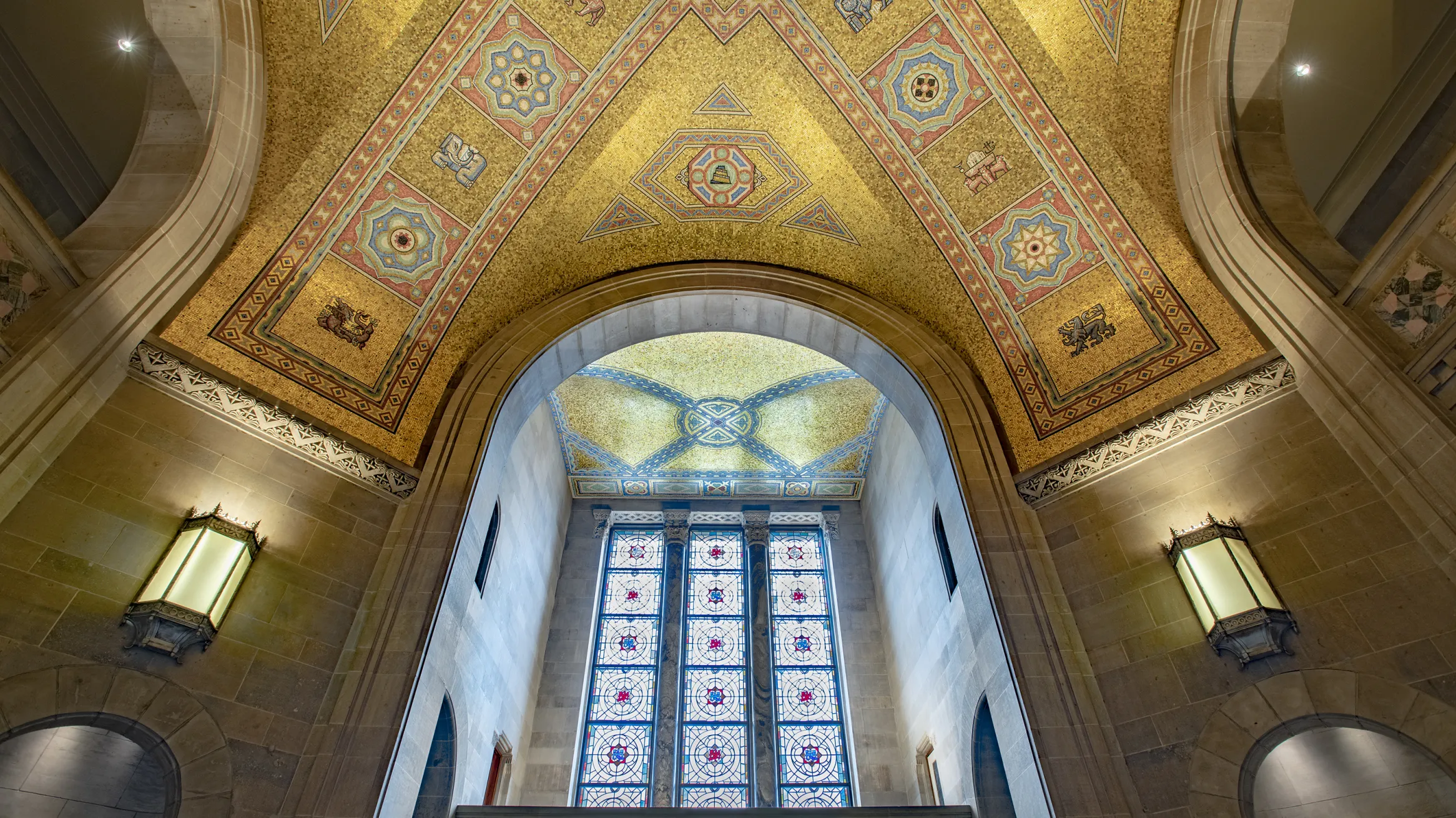 The ceiling of the ROM Rotunda the gold tiles shimmer in the light coming through the stain glass window.