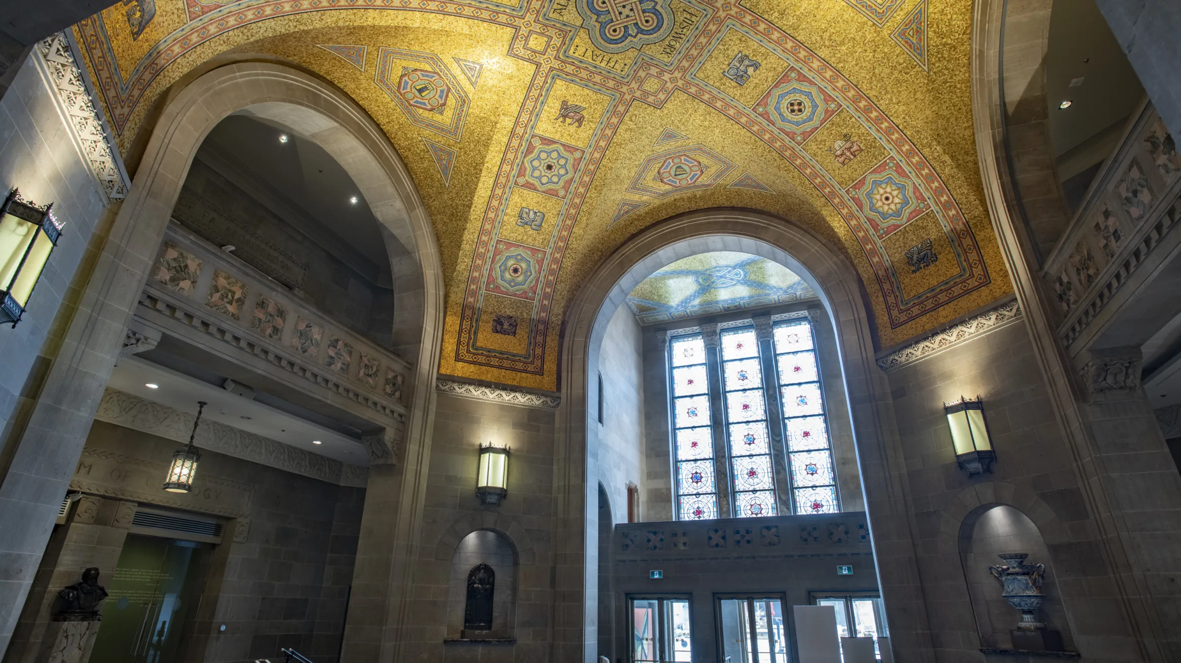 The ceiling of the ROM Rotunda the gold tiles shimmer in the light coming through the stain glass window.