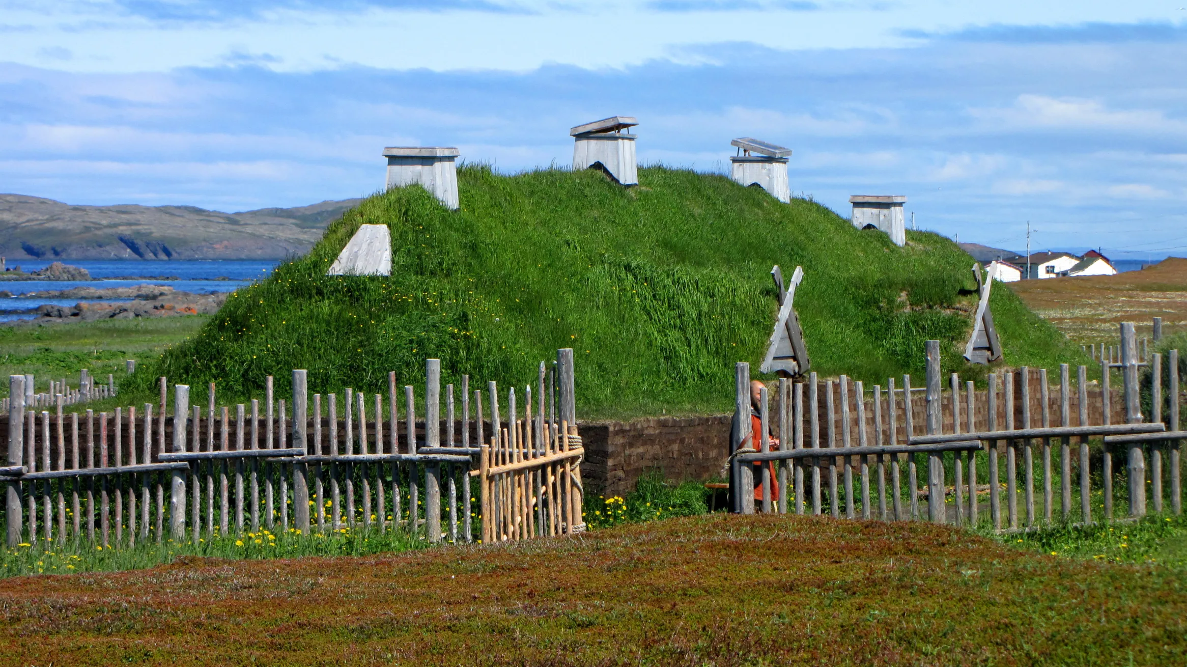 A dwelling with a grass-topped roof, surrounded by a fence.