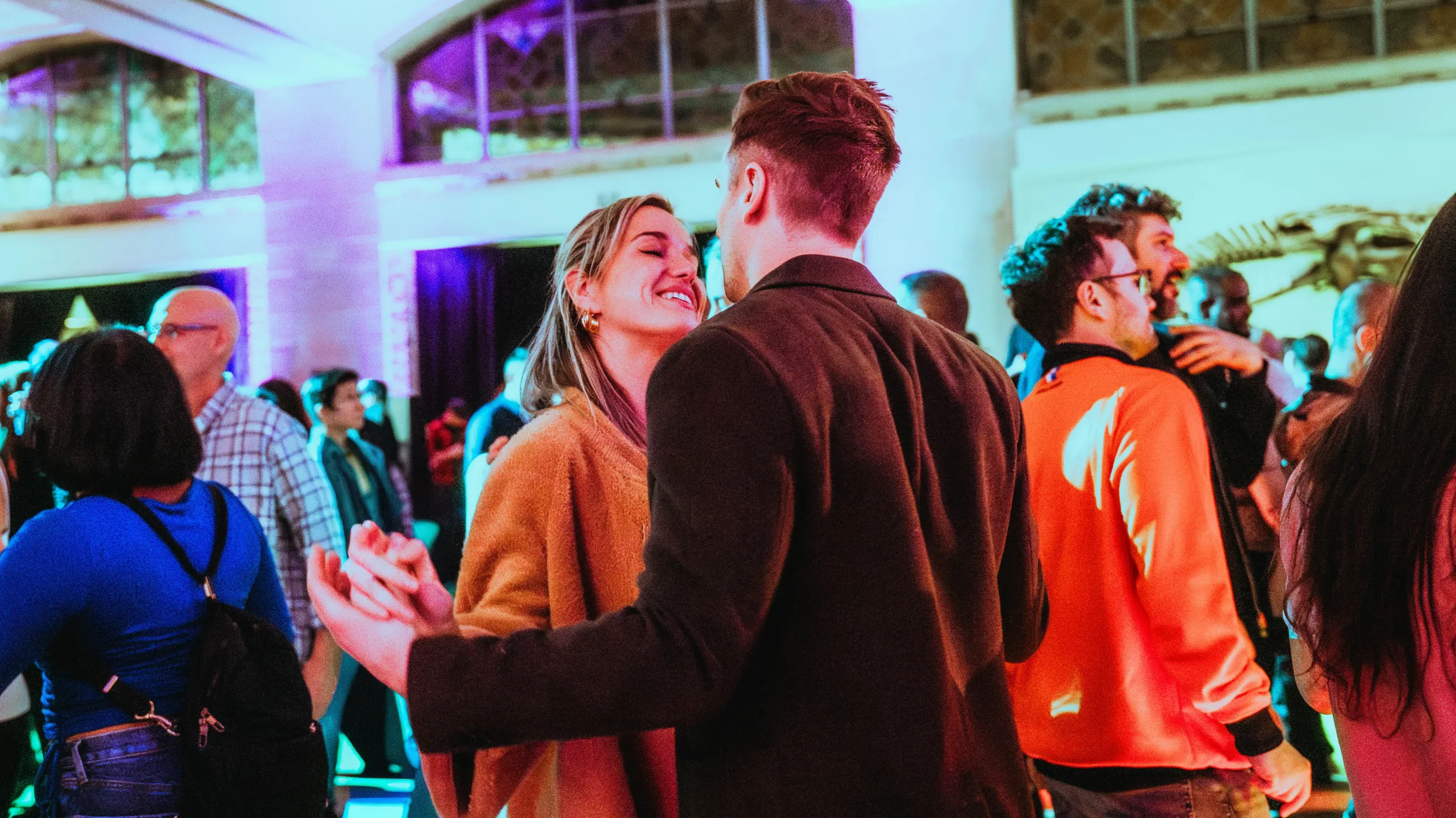 Couple locking hands in a crowd at a museum.