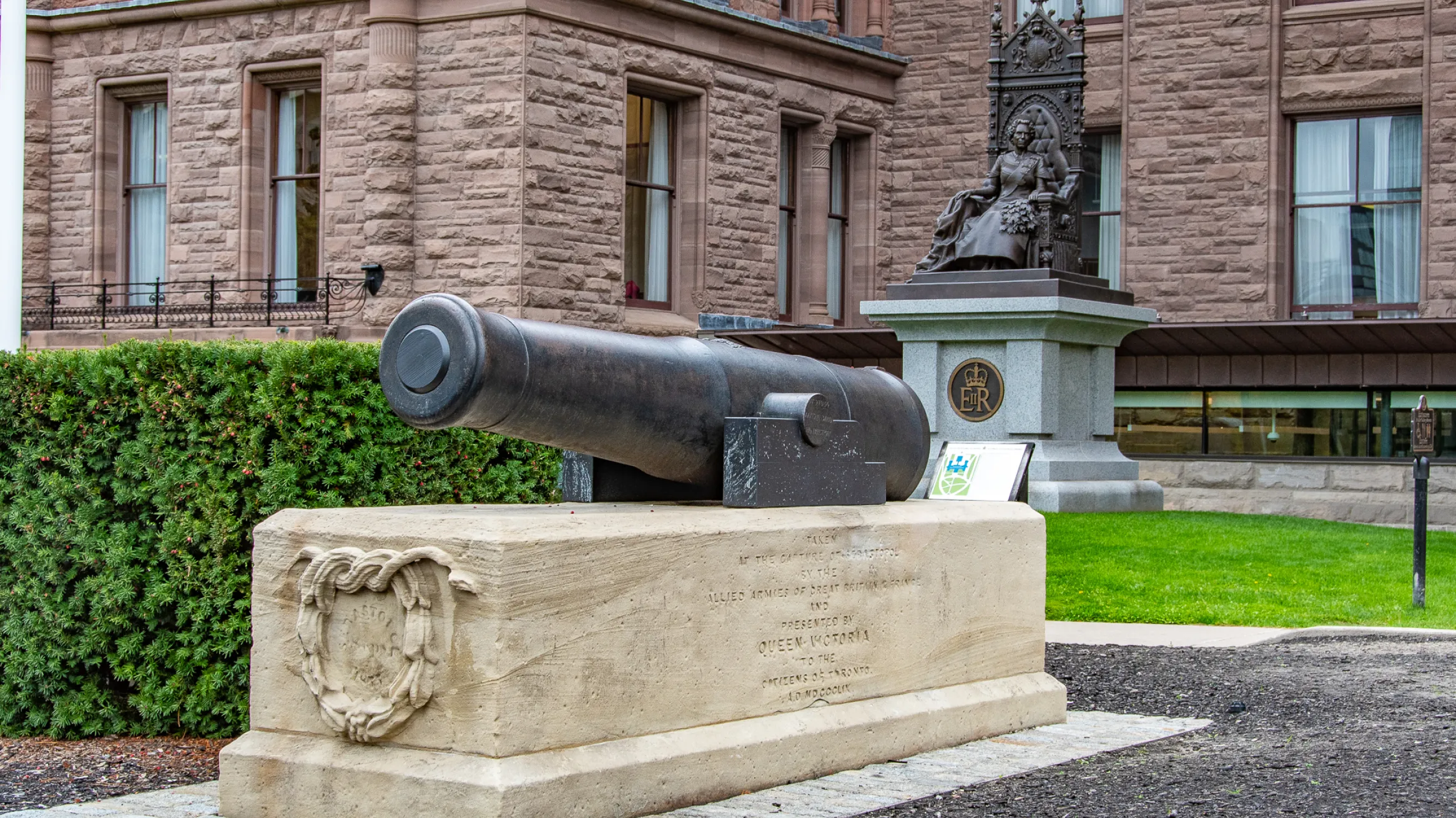 Canon in foreground with statue and building in background